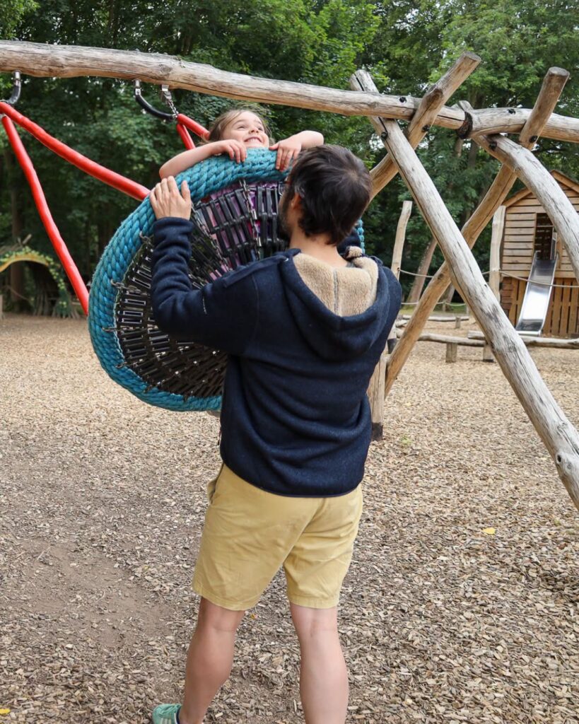 Child enjoying the woodland adventure playground with an adult at Audley End Enchanted Railway's Summer Festival.