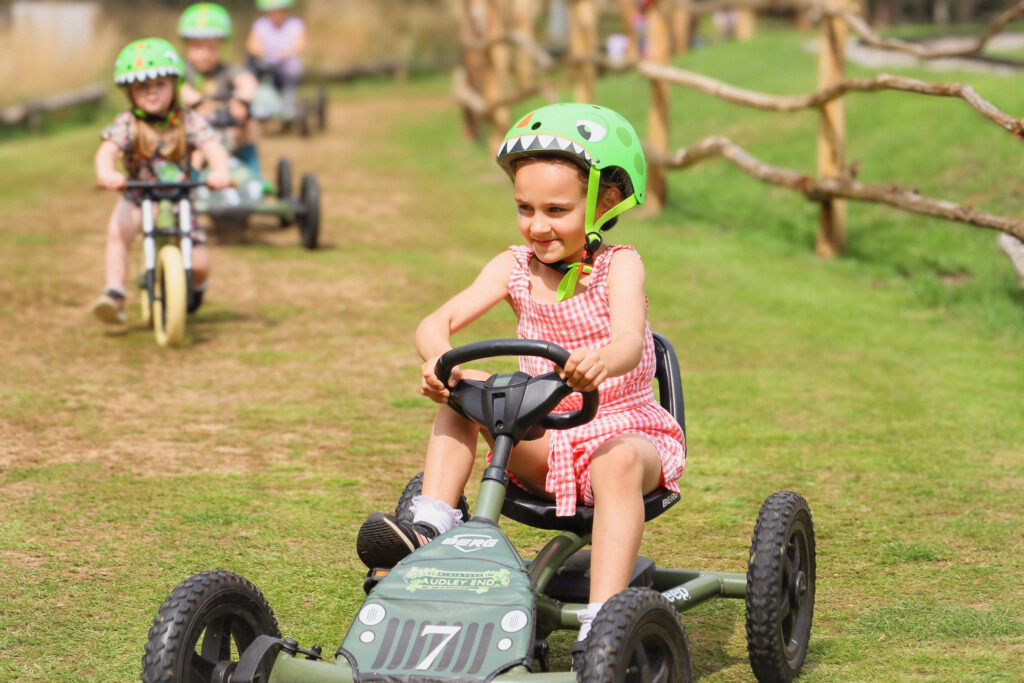 Children racing pedal go-karts on the Railway Racers track at Audley End Enchanted Railway during the Summer Festival.