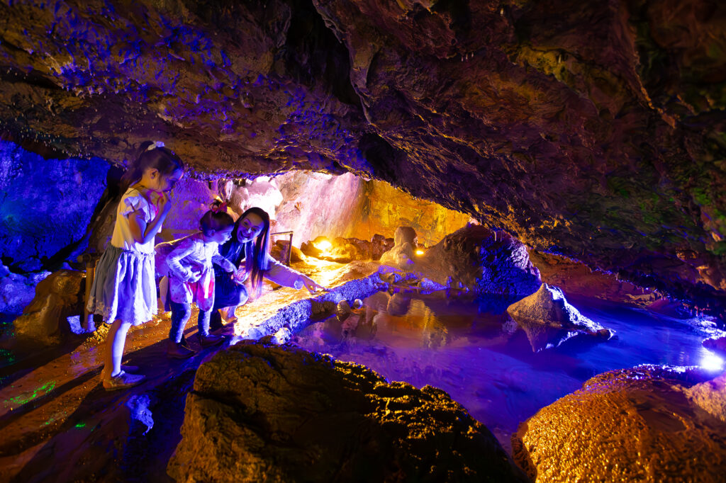 Family exploring the colourful underground caves at Wookey Hole in Somerset