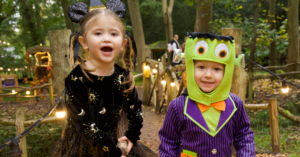 Two kids dressed up in Halloween costumes walking through forest