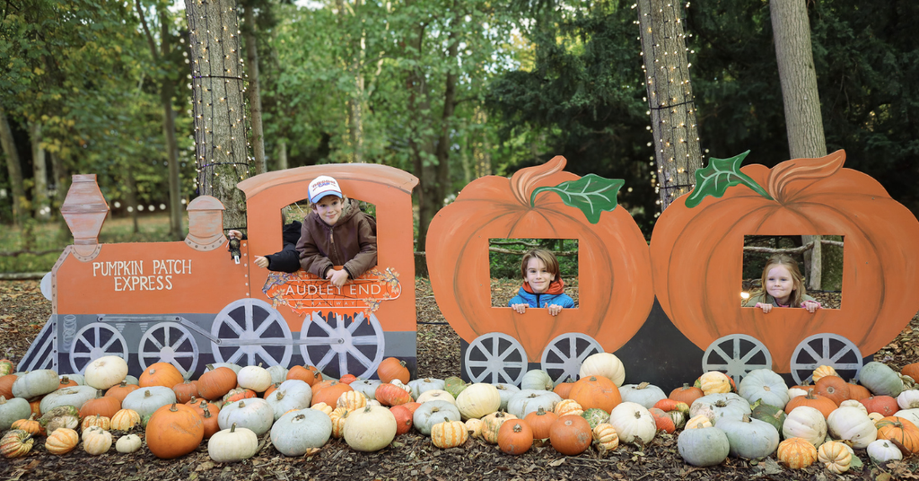 Three children posing in the Pumpkin Patch Express photo display at Audley End Enchanted Railway’s Halloween Special, surrounded by colourful pumpkins and autumn woodland decorations.