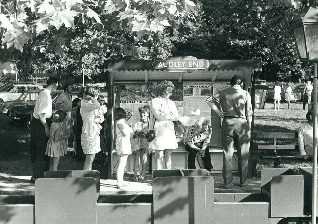 Historic black-and-white photograph of families and visitors gathered around the original Audley End Railway ticket kiosk in Essex, showing the railway's early years as a popular family attraction.
